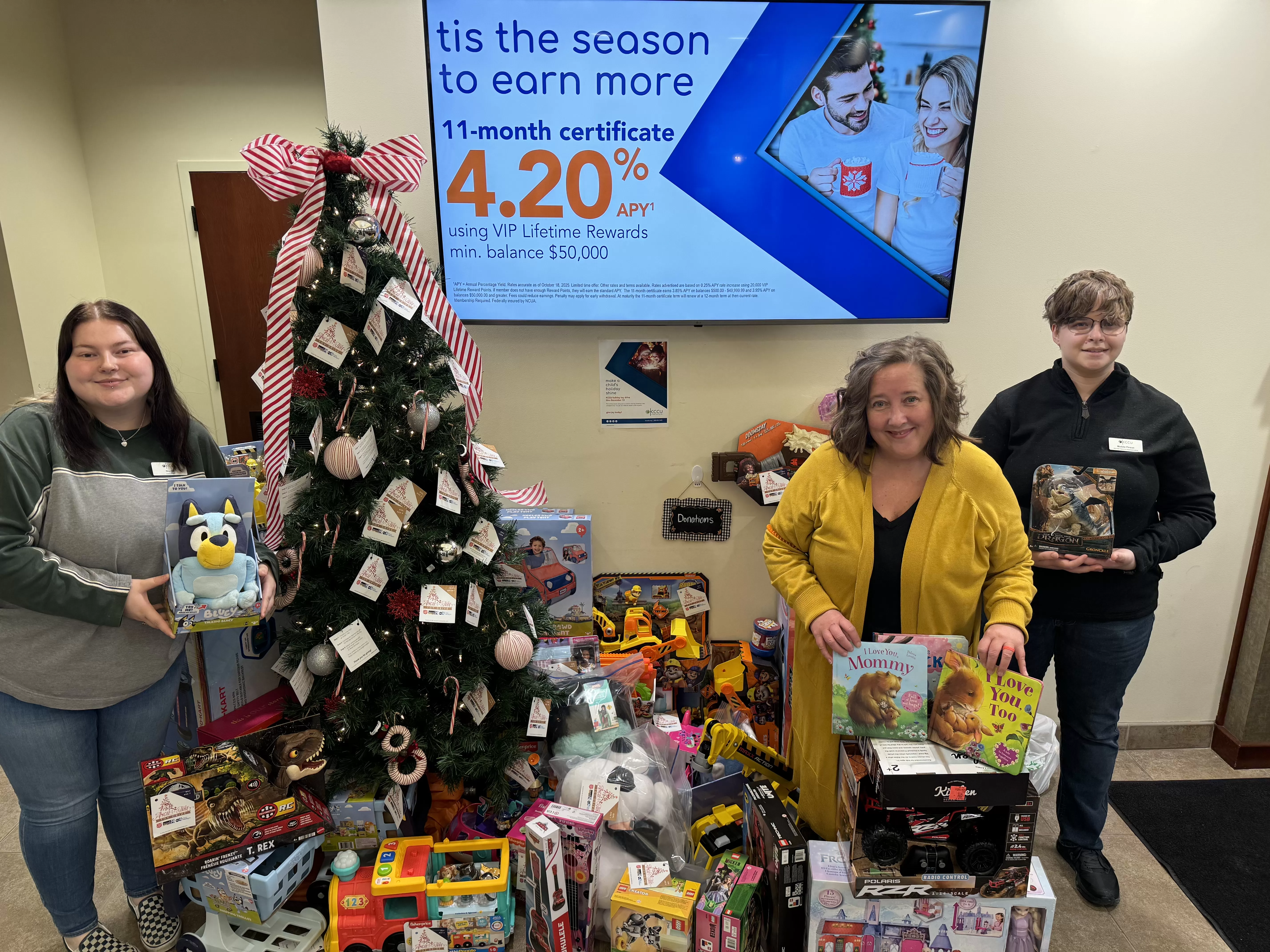 KCCU Team Members standing by Christmas Tree with toy donations